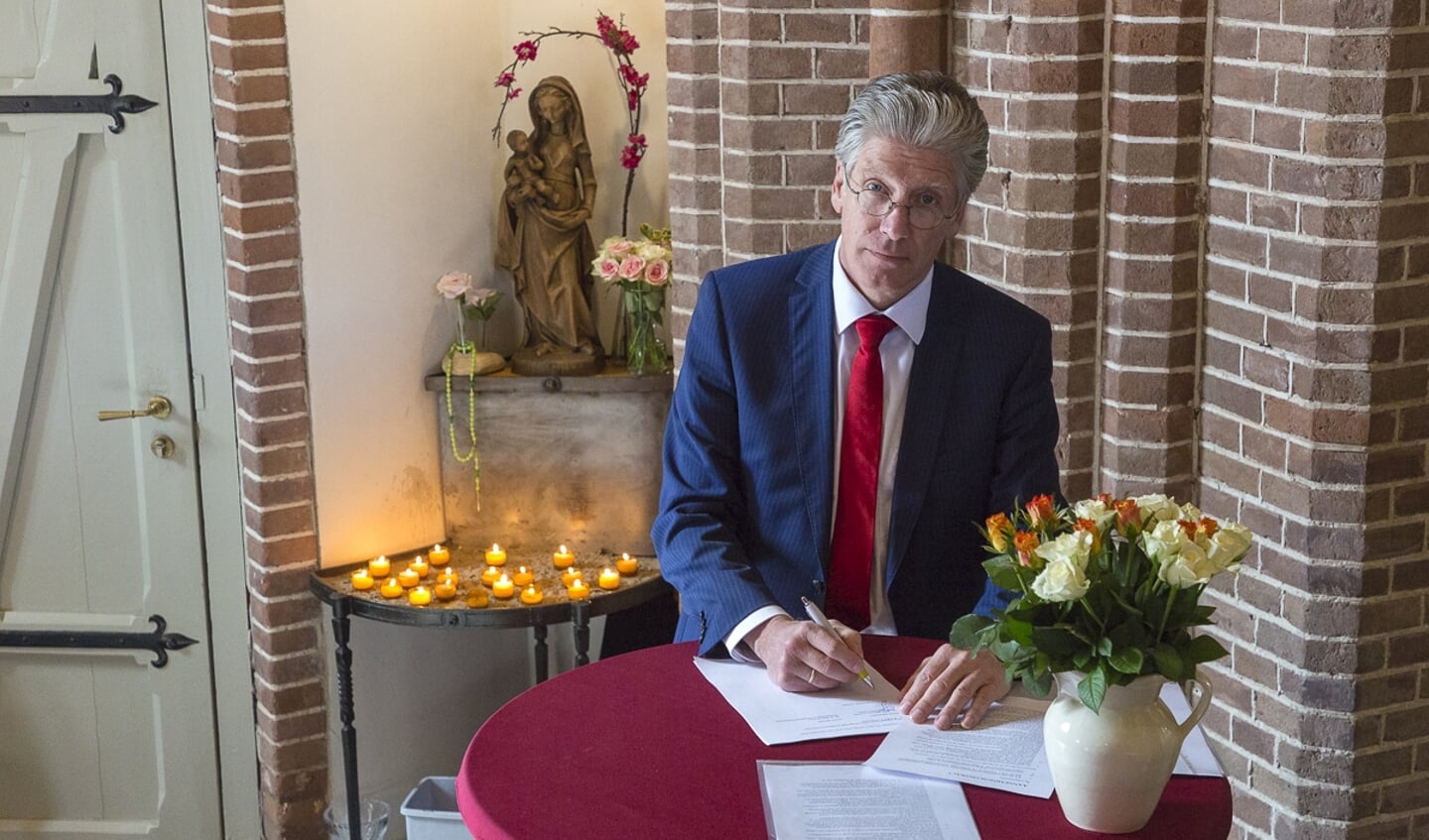 Secretaris van het parochiebestuur Hans ten Rouwelaar tekent het contract in de torenkapel van de Urbanuskerk.