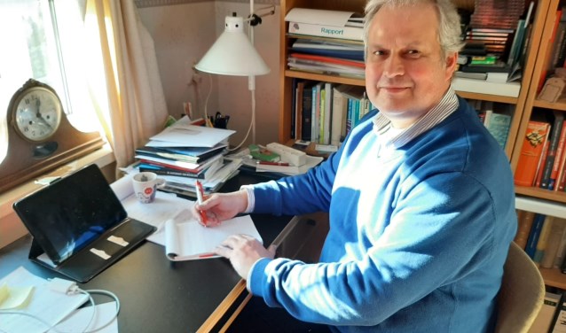 Wim Oosterwijk achter het bureau op zijn werkkamer.