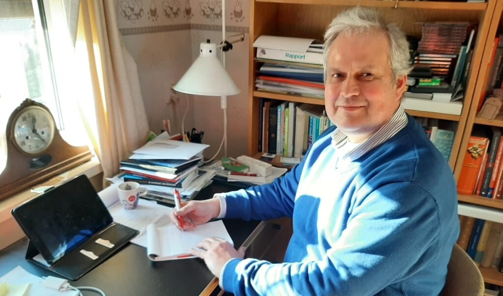 Wim Oosterwijk achter het bureau op zijn werkkamer.