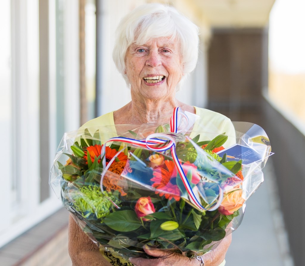 Annie van Dijk neemt haar bloemen in ontvangst.
