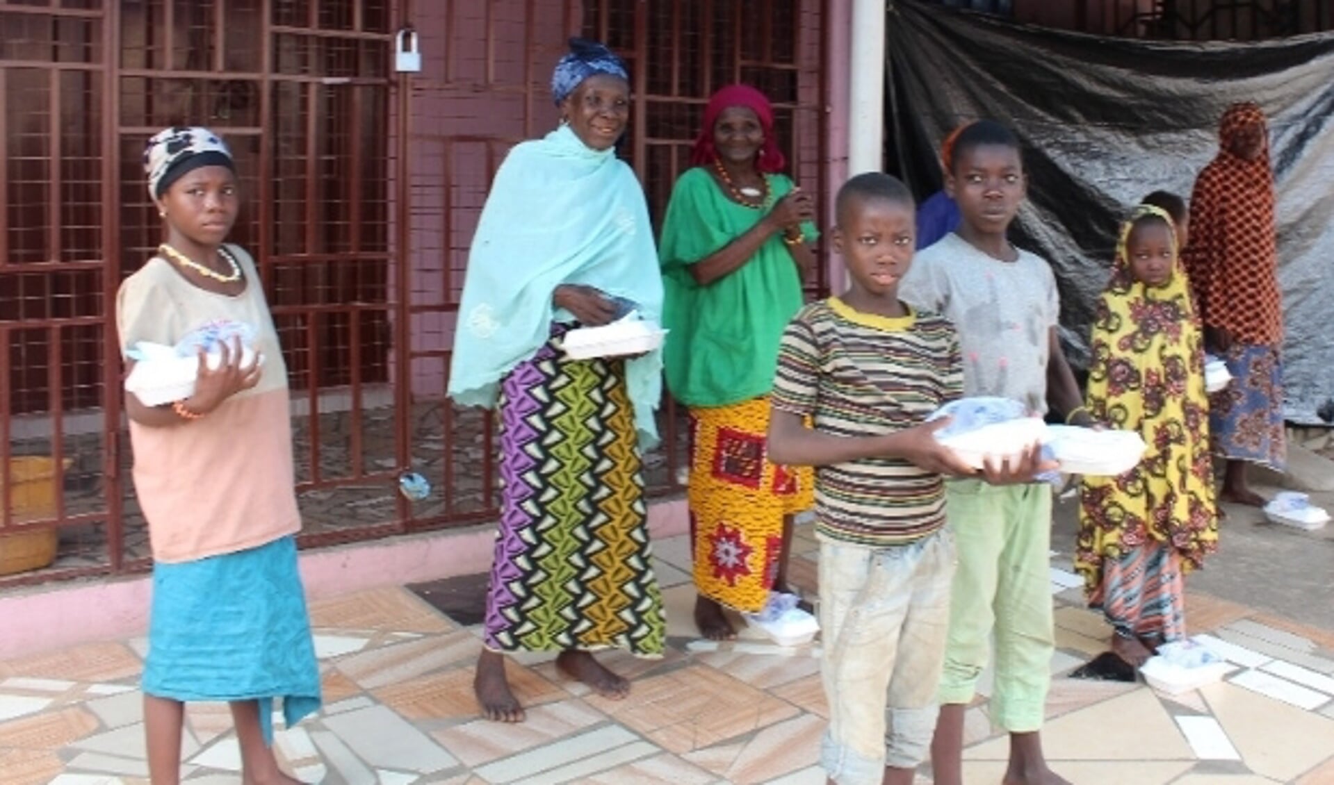 Dakloze kinderen en hun verzorgers nemen voedsel en water in ontvangst in Ghana