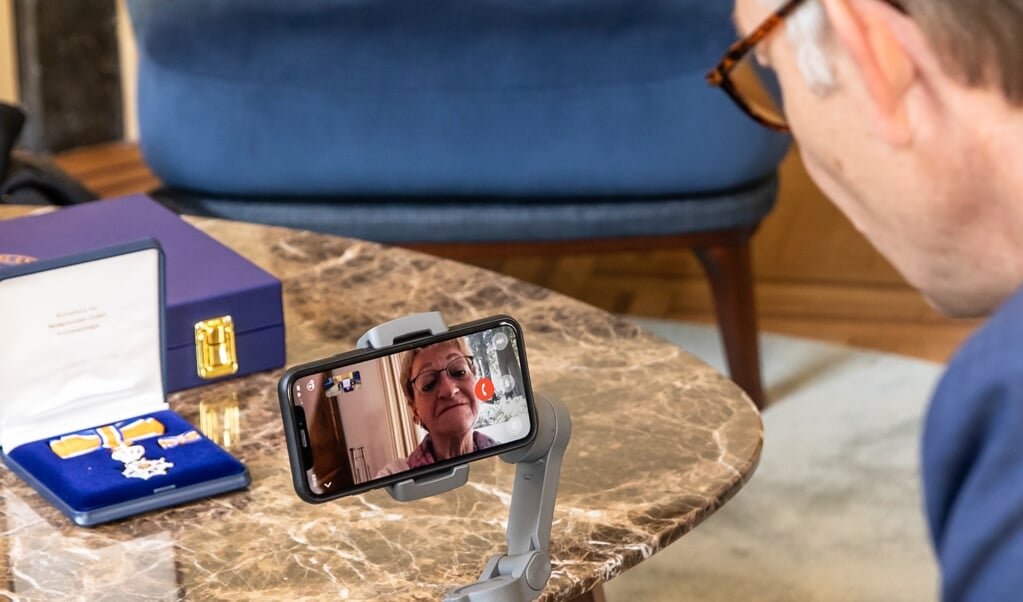 Burgemeester Mark Röell reikt digitaal een lintje uit aan Lisette Kuizinga-Claassens via de beeldtelefoon.