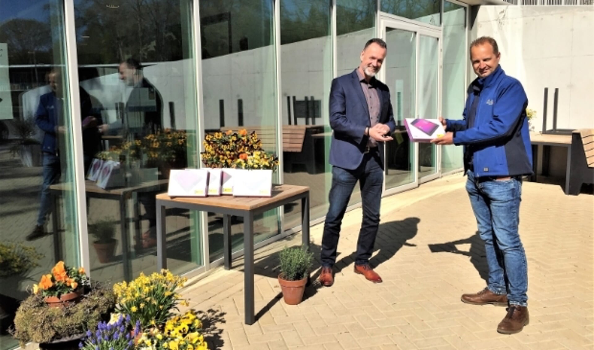 Coen Hooijer (rechts) overhandigt namens de firma Hooijer Renkum B.V. een vijftal iPads aan Hans Somer, lid van de Raad van Bestuur van Zinzia Zorggroep.