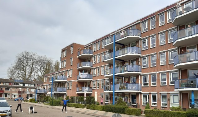 Sportcoach Maarten Hendrickx en Marlies van den Heuvel laten de senioren van de Wielinghof op hun balkon bewegen.