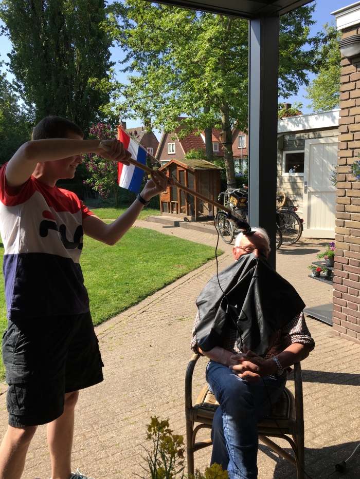 Opa zijn haar wordt op gepaste afstand eraf geschoren door kleinzoon Bas