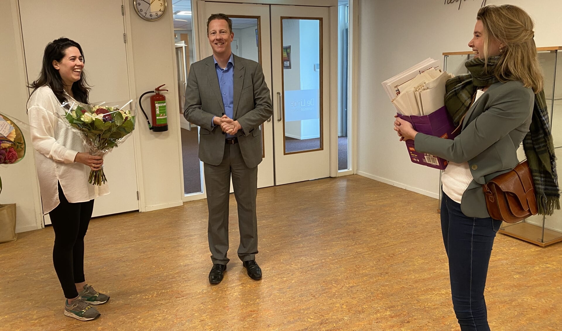 Wethouder Frank Berkhout en Marloes Smit geven directeur Bijlsma van de Linde een doos met Amstelkids.