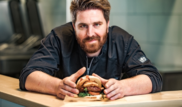 Henk van Keulen met een hamburger in de DINERfabriek.