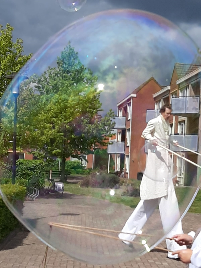 Steltloper Wit brengt op zijn stelten en met magische zeepbellen een glimlach op de gezichten van bewoners van De Lange Wei