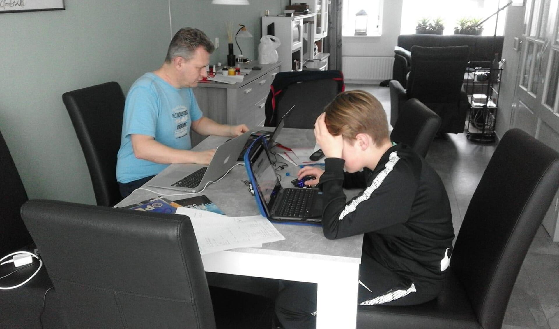 Roel Takken, docent Natuurkunde van het Johannes Fontanus College, verzorgt een online les en begeleidt tussendoor zijn zoon Youri bij zijn schoolwerk.