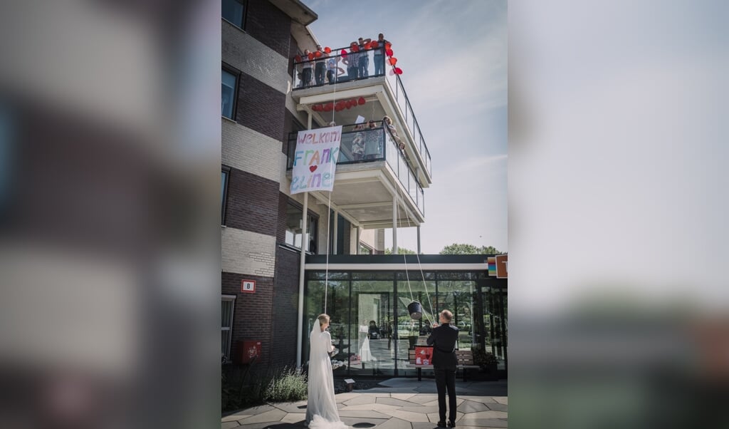 Het bruidspaar Eline en Frank Boudewijn met op de balkons bewoners en personeel van Thara. 