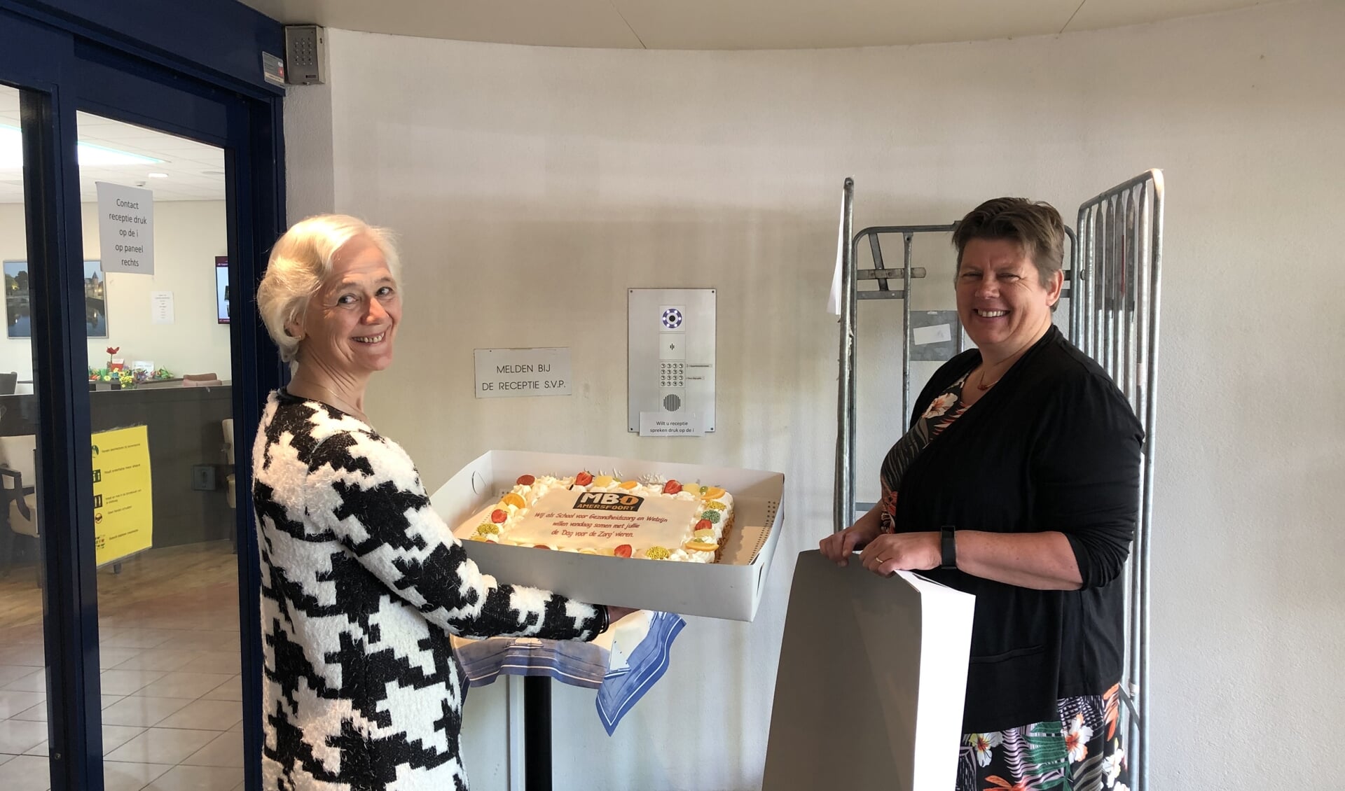 Yvonne Groot- Padberg, teamleider MBO Amersfoort, overhandigt de taart aan Mevrouw I.W.M. Vriens, bestuurder de Koperhorst. 