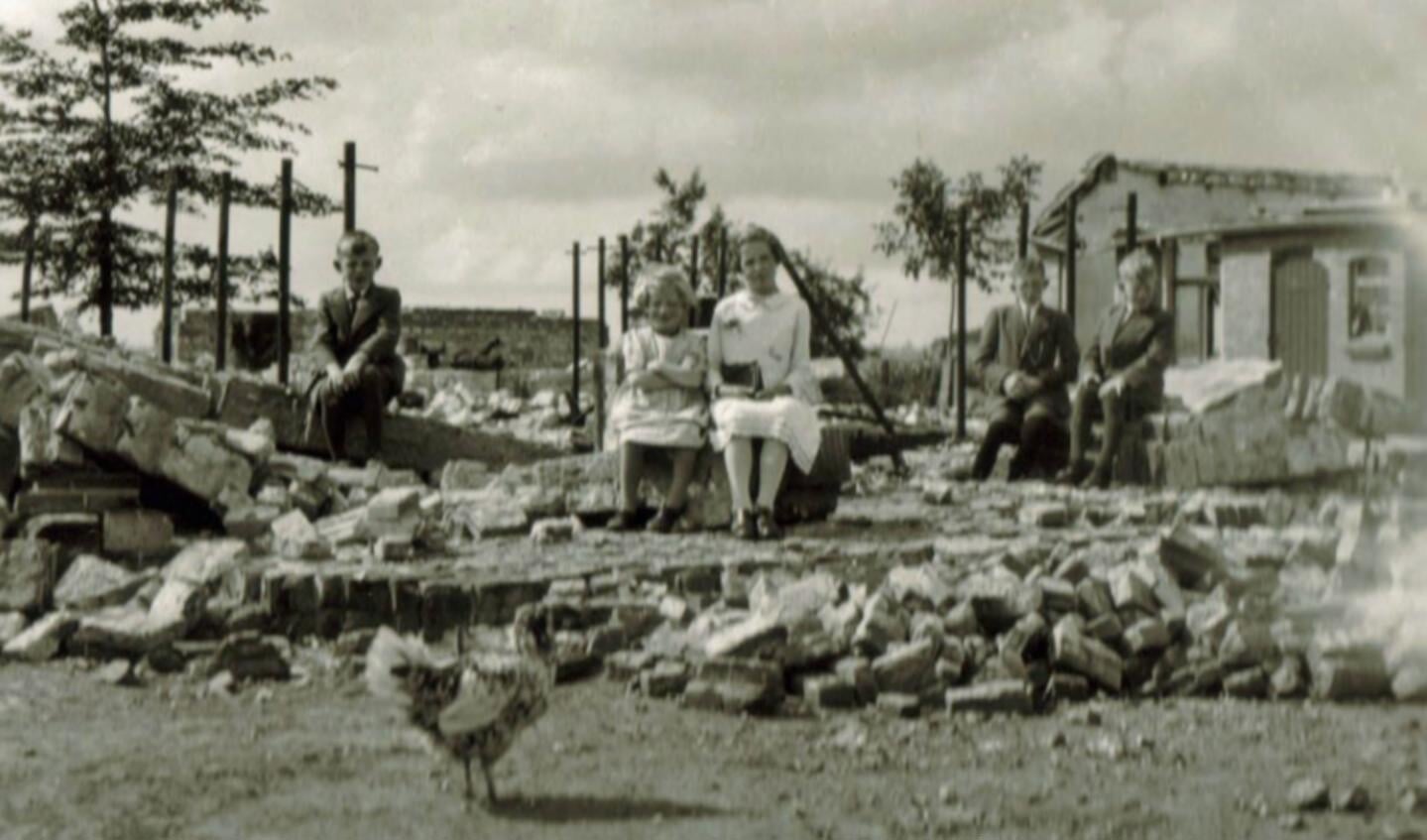 Foto 5: De kinderen van de familie Van Eijden – Johan, Marietje, Annie, René en Jan – poseren voor de foto op de ruïnes van wat voorheen hun ouderlijk huis was. Tijdens de strijd om de Grebbelinie in mei 1940 is ook hun boerderij uit 1926 verwoest.