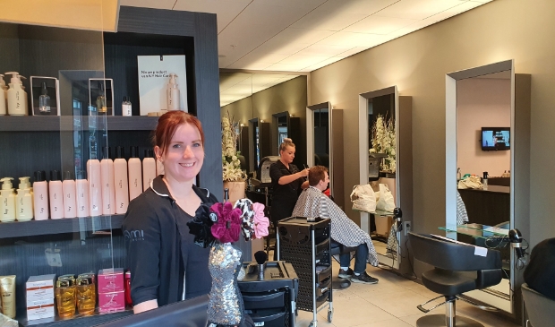 Renate Romeijn met op de achtergrond een collega die een klant behandelt. Iedereen is blij met de heropening.