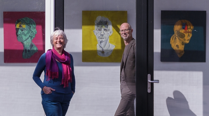 Emmy Bolsius en Anton Havelaar voor het werk van Nader Rikhtehgarchi. Op veilige afstand van elkaar, want gescheiden door glas.