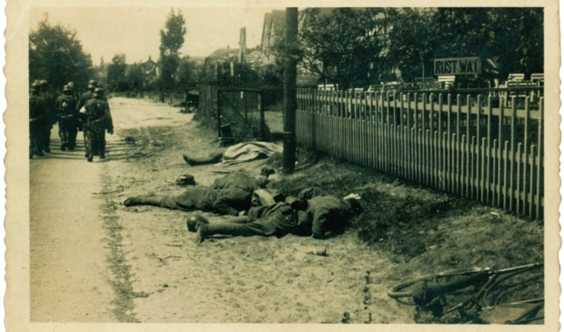 De gesneuvelde Nederlanders liggen bijeen aan de Grebbeweg, gezien richting Rhenen-stad. Nu is de locatie Bollee Events, De Nederlanders werden doodgeschoten in de tuin ernaast. (Foto uit boek/NIOD)