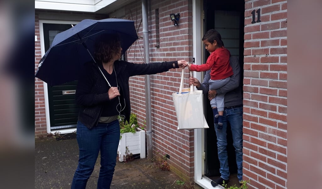 Femke Reijnen overhandigt de voorleestas aan een deelnemer van de VoorleesExpress.