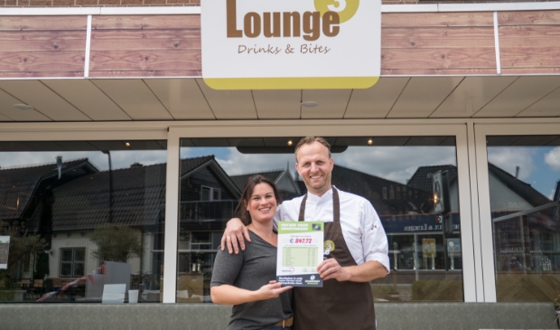 Adriëlle en Johan Brink van Lounge 3 met het presentatiebord waarop het ingezamelde geldbedrag en hun 'fietshelden' staan.