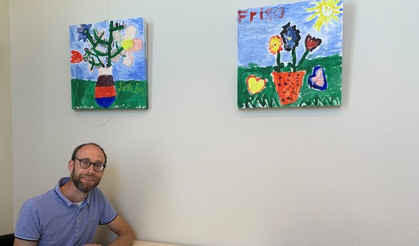 Wethouder André van Roshum onder de kunstwerken van zijn kinderen.