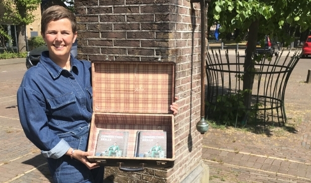 Bij de oude pomp op het Dorpsplein toont Linda Commandeur vol trots haar boek 'Connection Skills'.