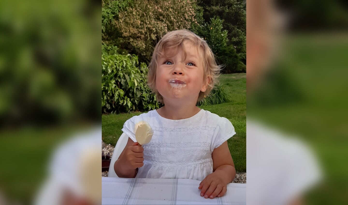 ,,Kleindochter Esmee geniet van een ijsje bij opa en oma in de tuin.