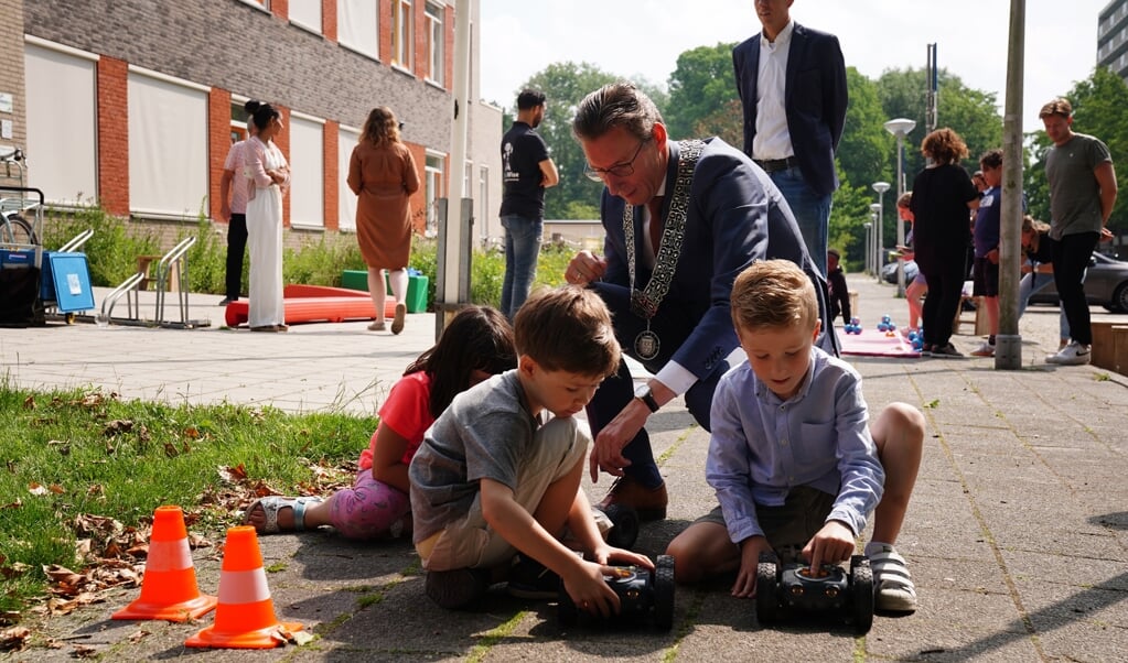 Kinderen van De Bloeiwijzer proberen de robots uit samen met de burgemeester.