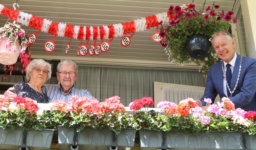 Burgemeester Mark Röell op het balkon met Greet en Jaap Post die hun 65-jarig huwelijksfeest vieren. 