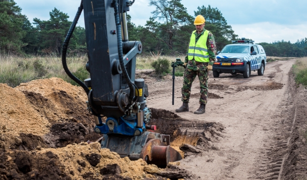 Een medewerker van de EOD 'scant' het volgende stukje van het zandpad.