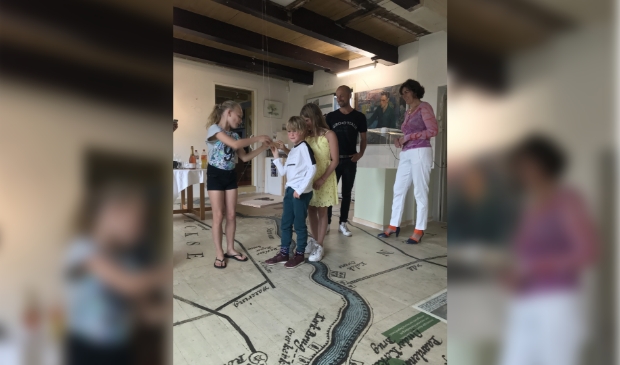 Vloersponsor Rogier en Groen en wethouder Marian van der Weele kijken toe hoe de kinderen Groen de nieuwe museumvloer ‘openen’.