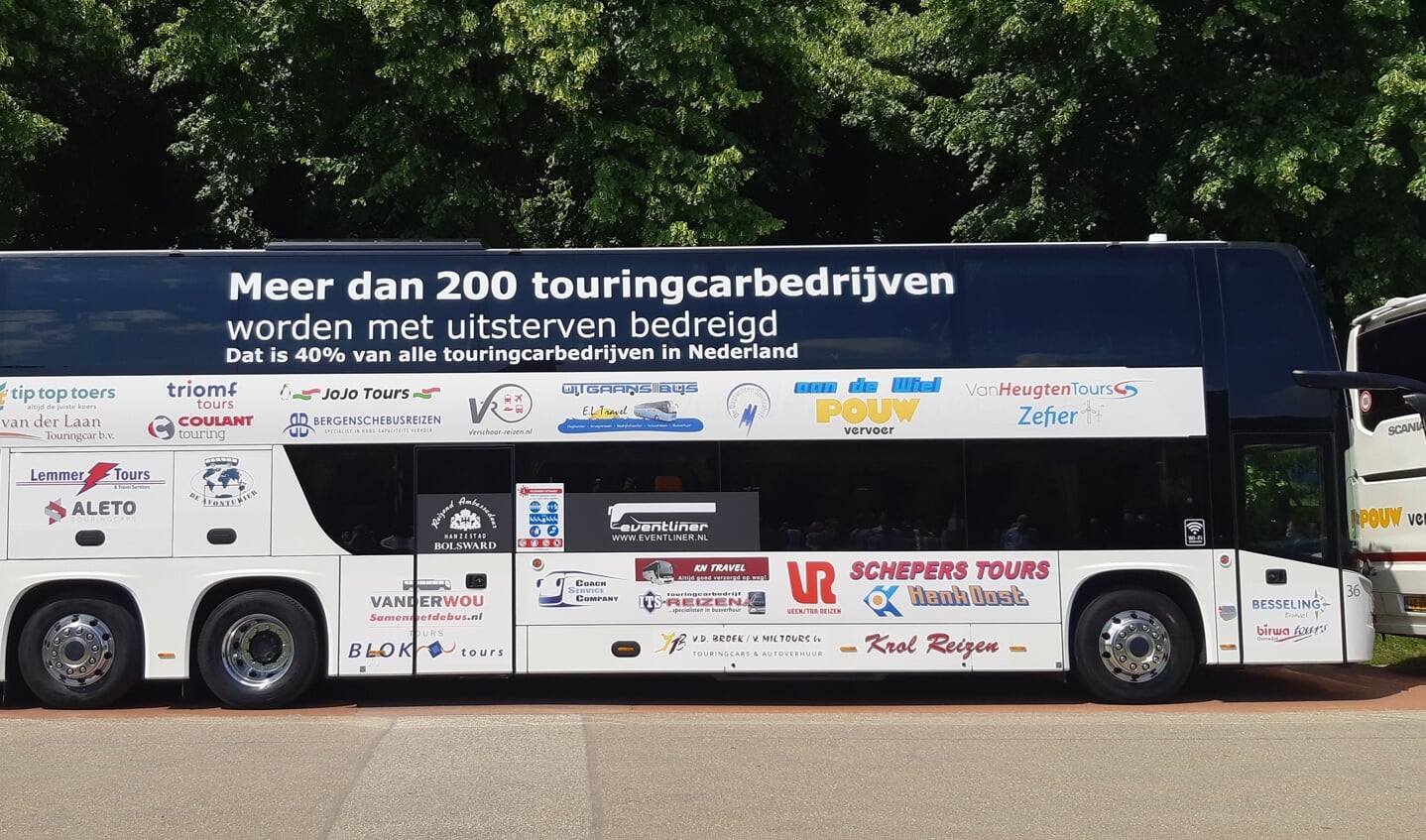 Een dubbeldekker met logo's van alle touringcarbedrijven die deelnamen aan de 'toeteractie' in Den Haag.