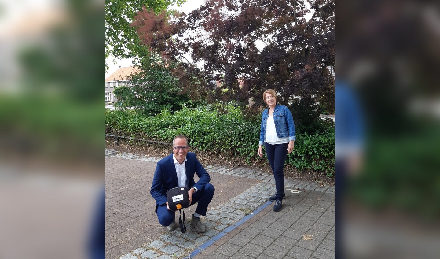 Wethouder Harke Dijksterhuis met een AED in zijn handen, naast hem staat Rietha Dasselaar, voorzitter van de Stichting AED Nijkerk-Hoevelaken.
