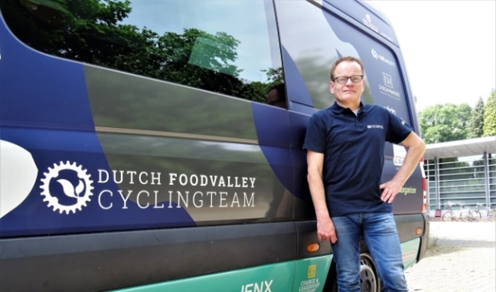 Teammager van het Dutch Food Valley Cycling Team, René Bastiaansen, poseert trots bij de nieuwe teambus.