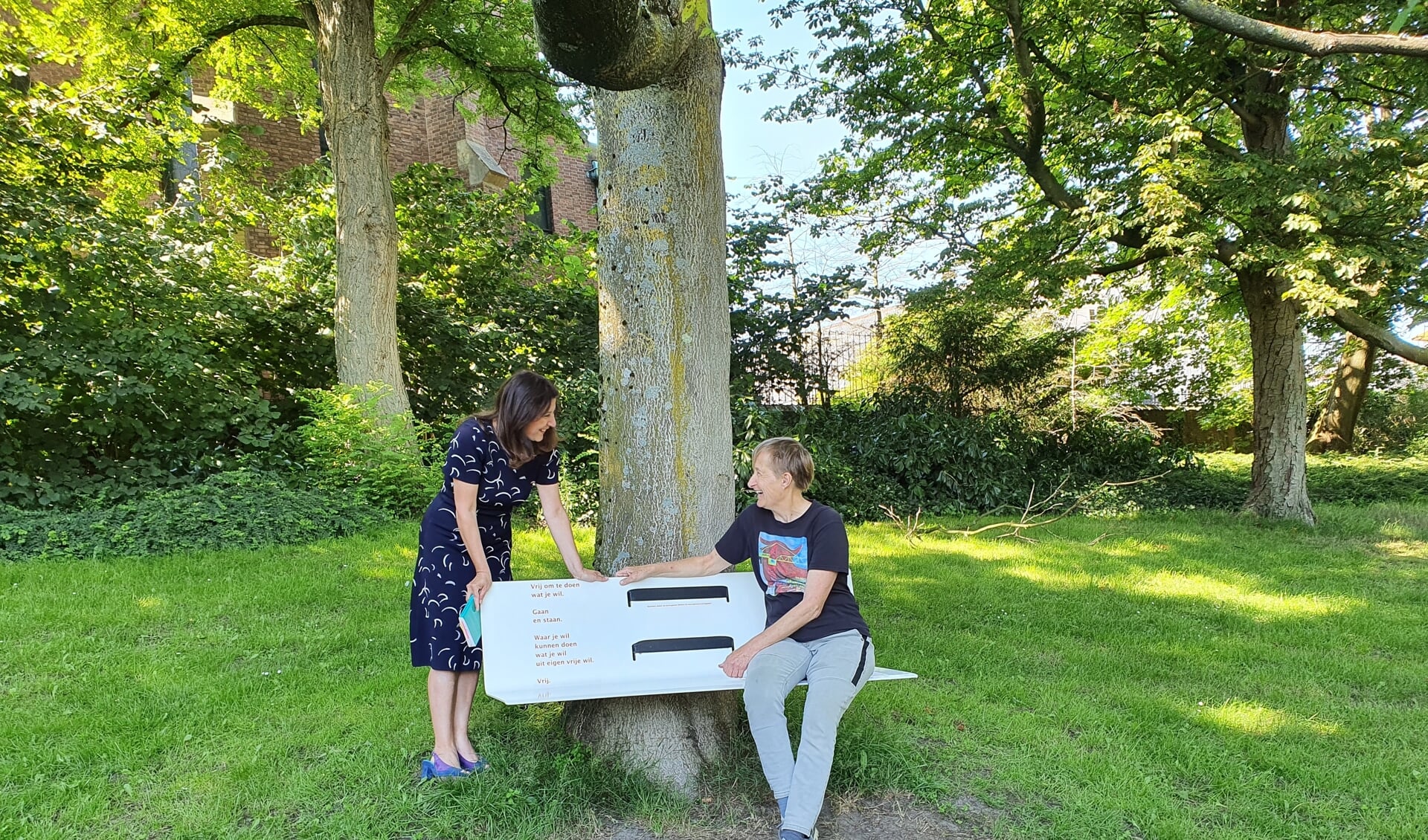 Wethouder Koser Kaya met Noortje, van wie een gedicht op de bank is afgedrukt. 