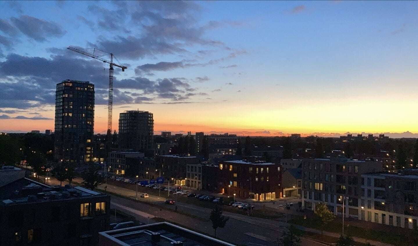 ,,Eind maart 2020 ben ik verhuisd naar de Operaweg, nieuwbouwflat de Dirigent in de nieuwe wijk ‘Hogekwartier’. De eerste maanden en de eerste zomer in deze flat. Vanaf het begin van de middag zon tot deze achter de horizon verdwijnt vanaf de zevende verdieping. Heerlijke, lange, zomerse avonden waar je, zoals op de foto te zien is, om 22.30 uur nog een prachtig uitzicht kan hebben. Dit is één van de vele foto’s die ik gemaakt heb van dit uitzicht; wat voor mij bijzonder is, omdat ik nog elke dag mag genieten van dit mooie uitzicht en dit graag met anderen deel!