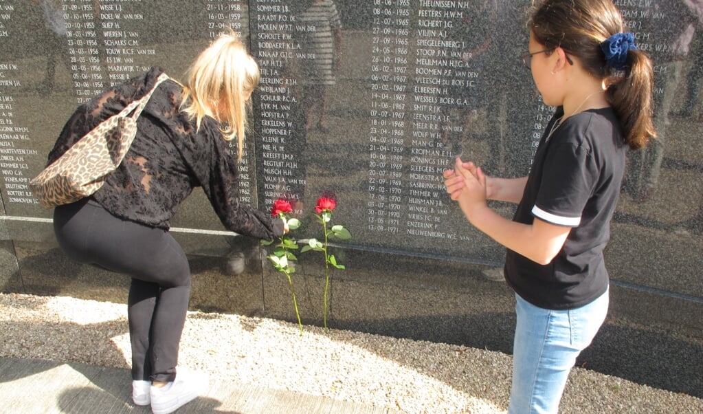 Twee kleinkinderen van vlieger Paul Dirks leggen rozen bij monument Soesterberg.