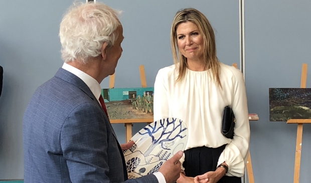 Gerrit Valk, voorzitter van de Raad van Bestuur van Veteraneninstituut, overhandigt koningin Máxima een kunstwerk.