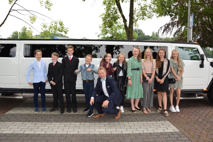 De groep 8 sterren poseren met hun leerkracht voor de stoere limousine