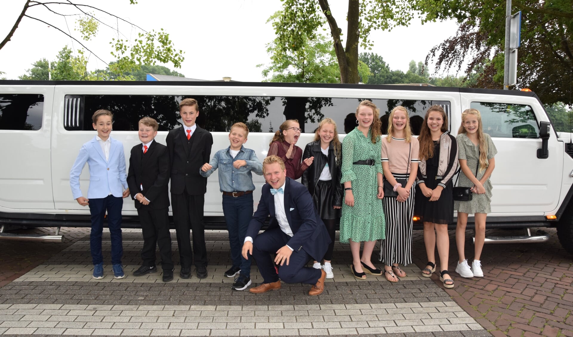 De groep 8 sterren poseren met hun leerkracht voor de stoere limousine
