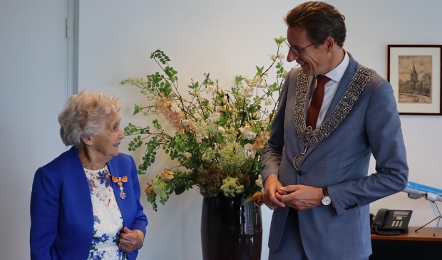 Burgemeester Poppens reikt een lintje uit aan Moppie Holla-Fontijn.