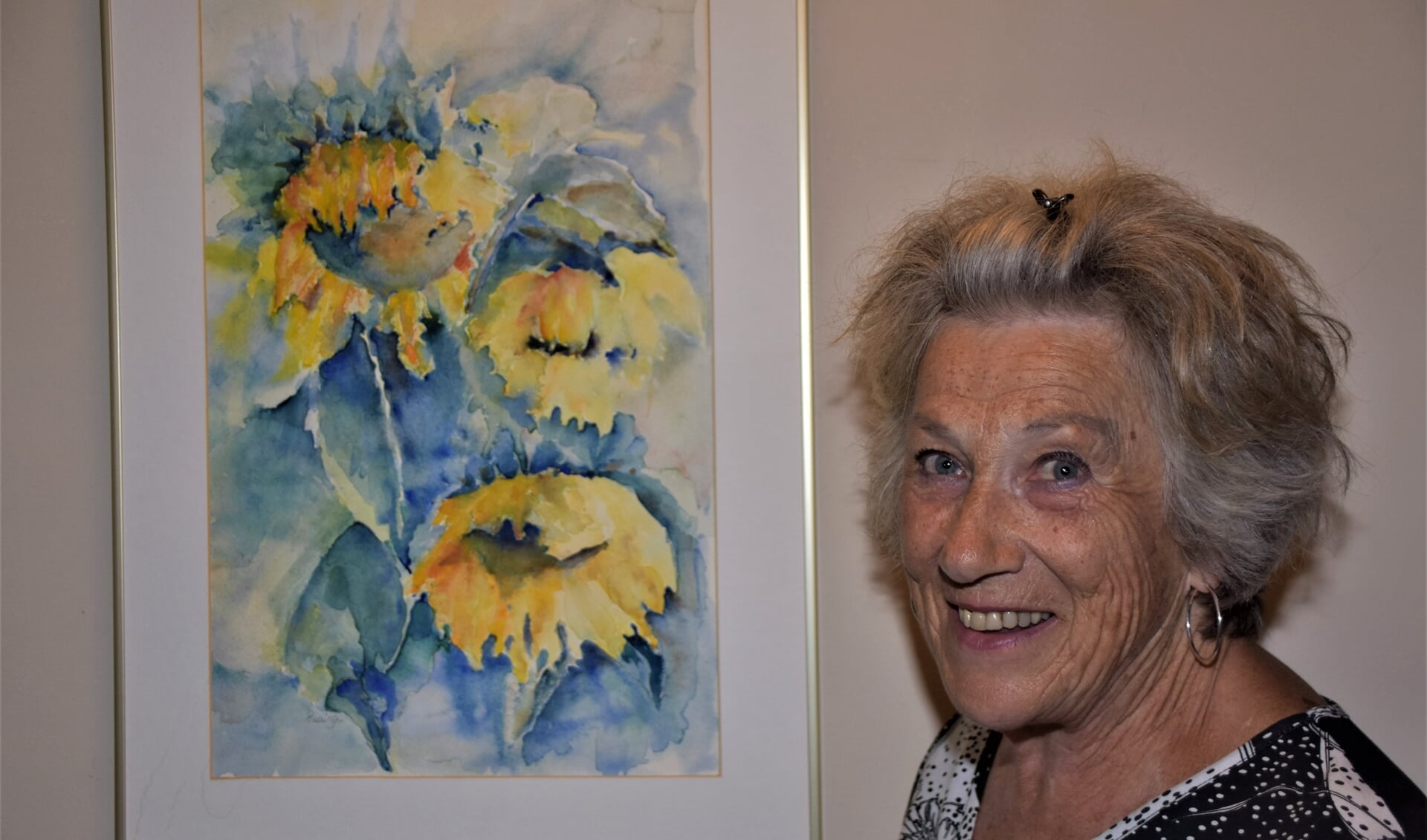 Lia Dunnewijk bij een van haar schilderijen die te zien zijn in De Drie Eiken. De Soesterbergse schildert vrolijke stukken, volgens haar publiek.