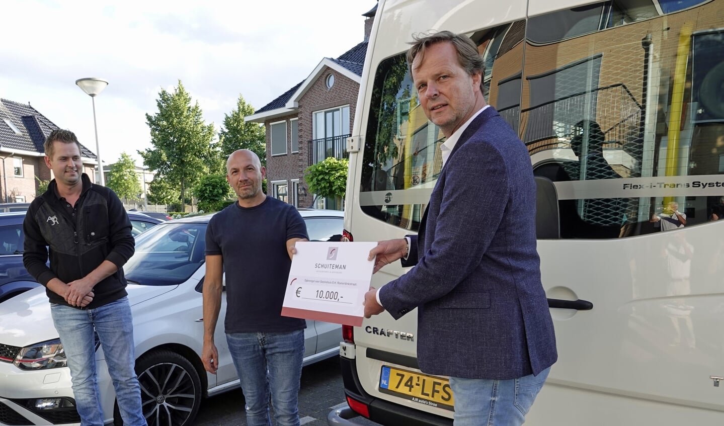 Links Arnoud Ruiter van AJR Auto's in Stroe, die de rolstoelbus heeft geleverd, in het midden gezinsouder Vasile, rechts vice-voorzitter van het Schuiteman Wandelfestijn Voorthuizen Alex van de Kamp, die een cheque van 10.000 euro overhandigt.
