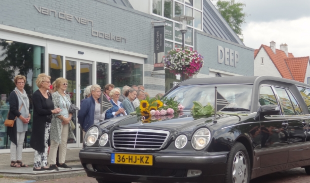 De rouwauto stopt even bij Boekhandel Van de Ven.