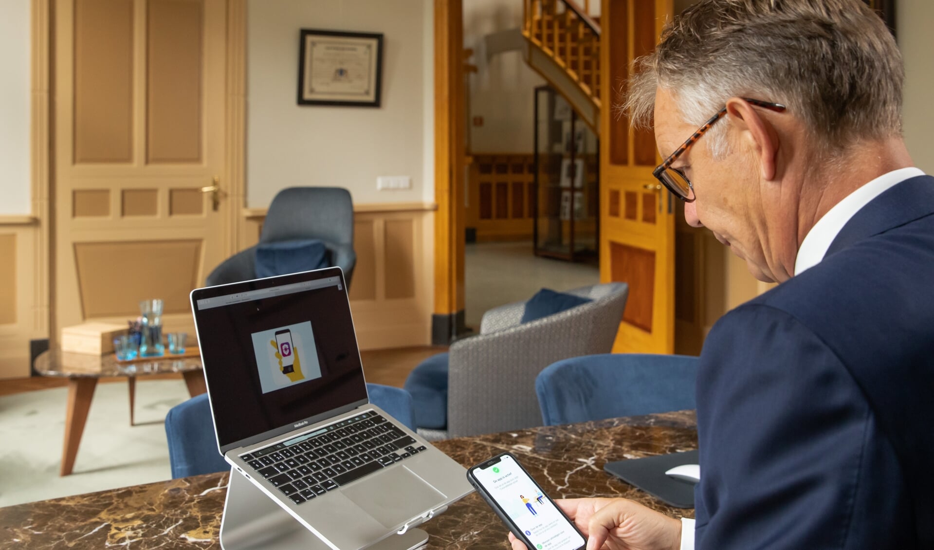 Burgemeester Mark Röell bij het installeren van de corona-app in zijn werkkamer, vorig jaar. 