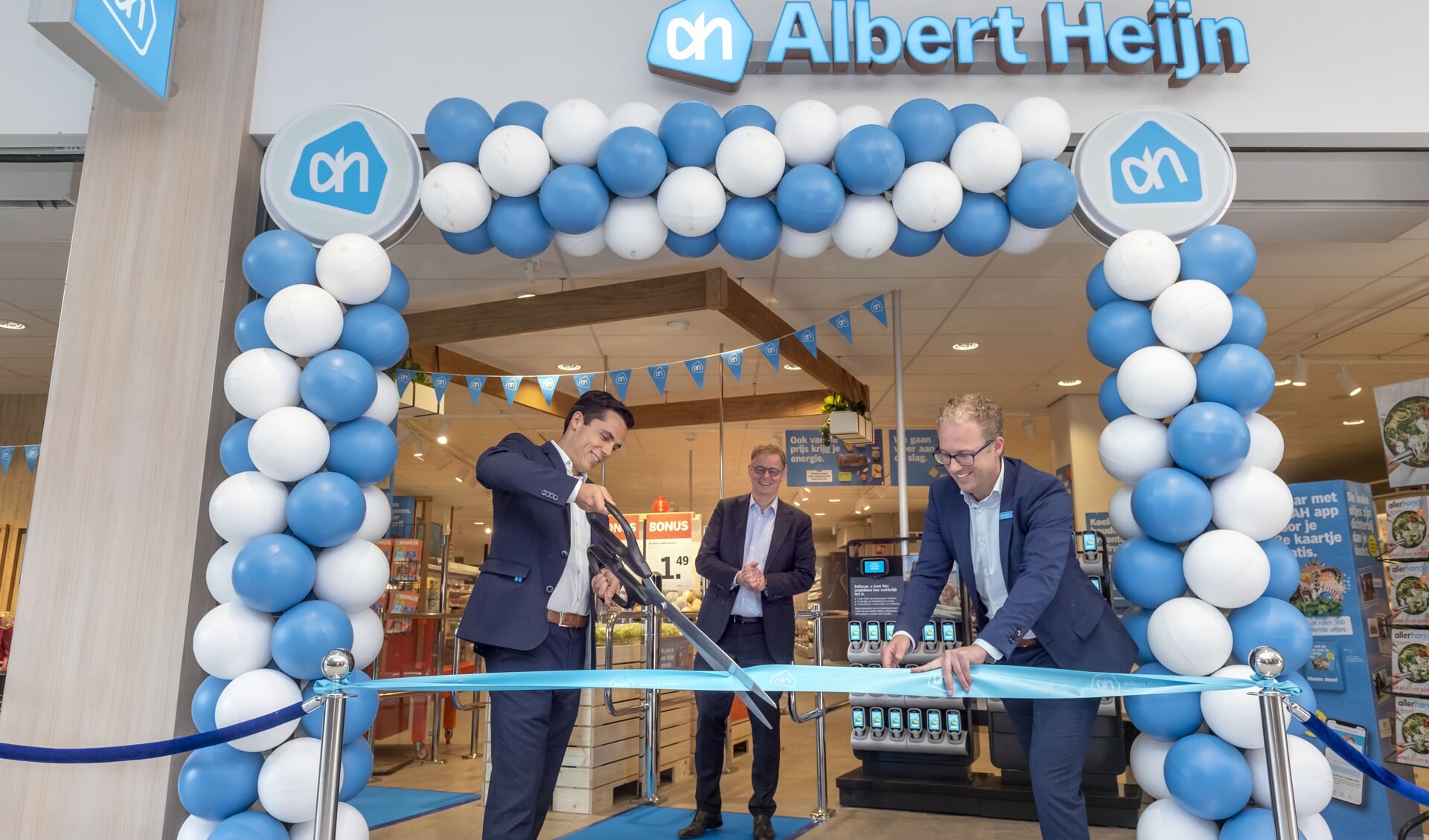 Supermarktmanager Dave Mazzavillani en zijn assistent Stefan Okkerse knipten samen het lint door van de vernieuwde Albert Heijn Groenhof. In het midden staat financieel directeur Albert Heijn Hendrik-Jan Roel. 