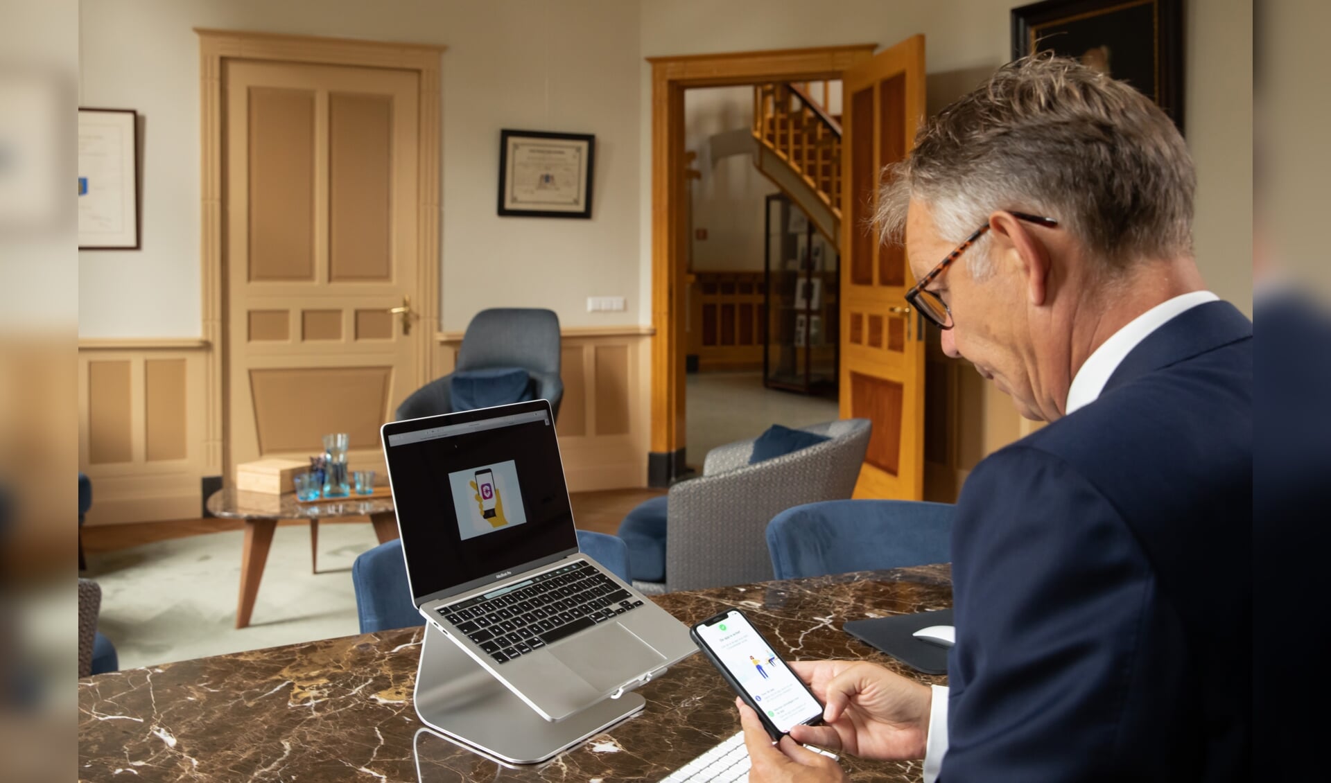 Burgemeester Mark Röell installeert de corona app in zijn werkkamer.