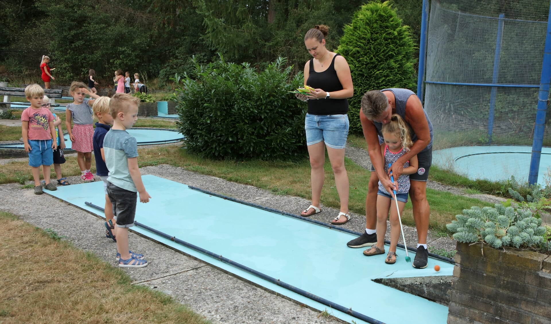 Irene de Jong leert een meisje midgetgolfen.