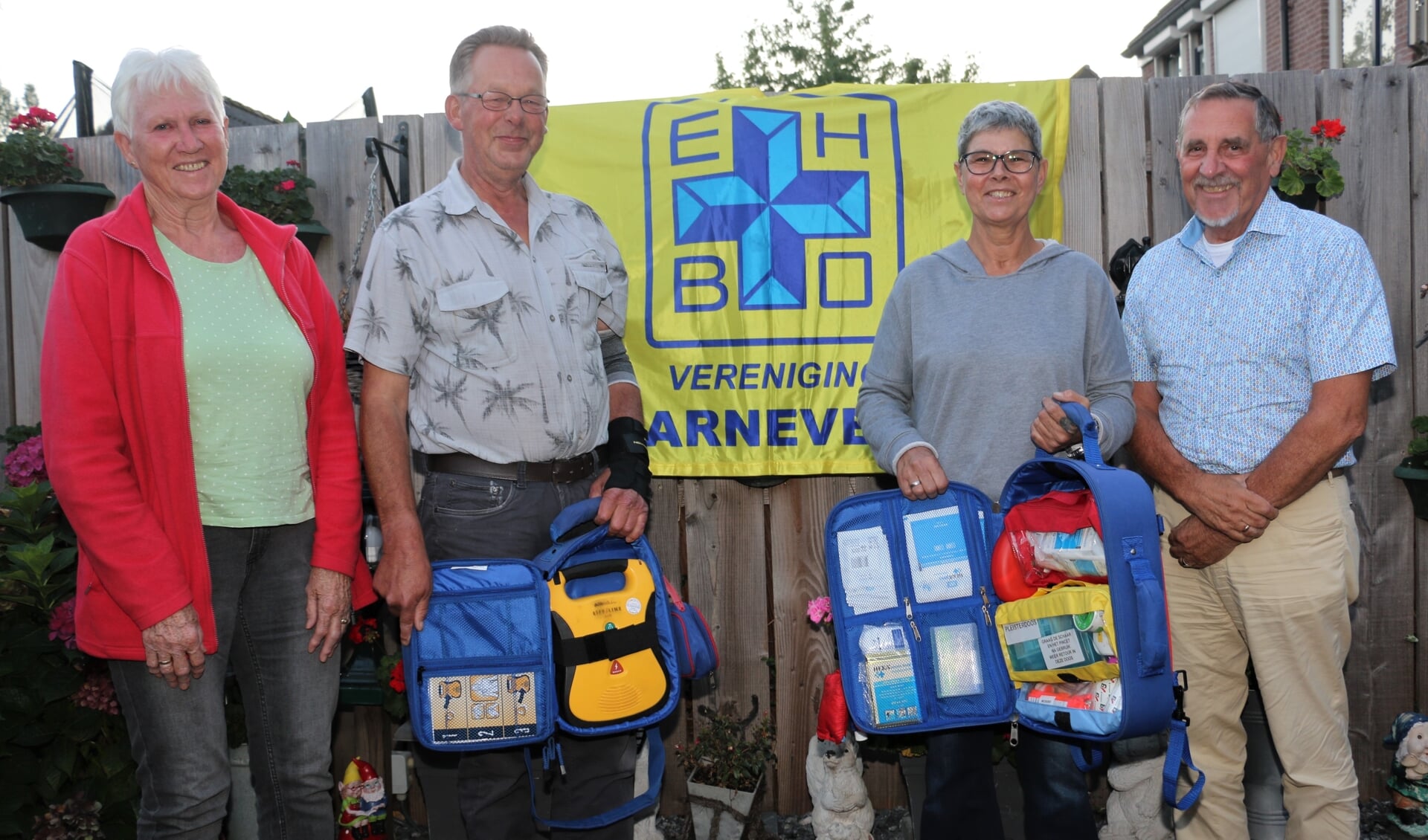 Vlnr: Marry van den Brink, Jan van Veluw, Sheila Koelewijn en Henk Morren, bij de EHBO-vlag en met AED-tassen.