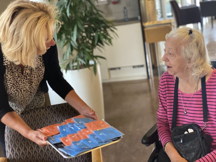Zorgdirecteur Helma Meeuwissen van A.G. Bodaan biedt een mondkapje aan aan een cliënt van Kennemerhart