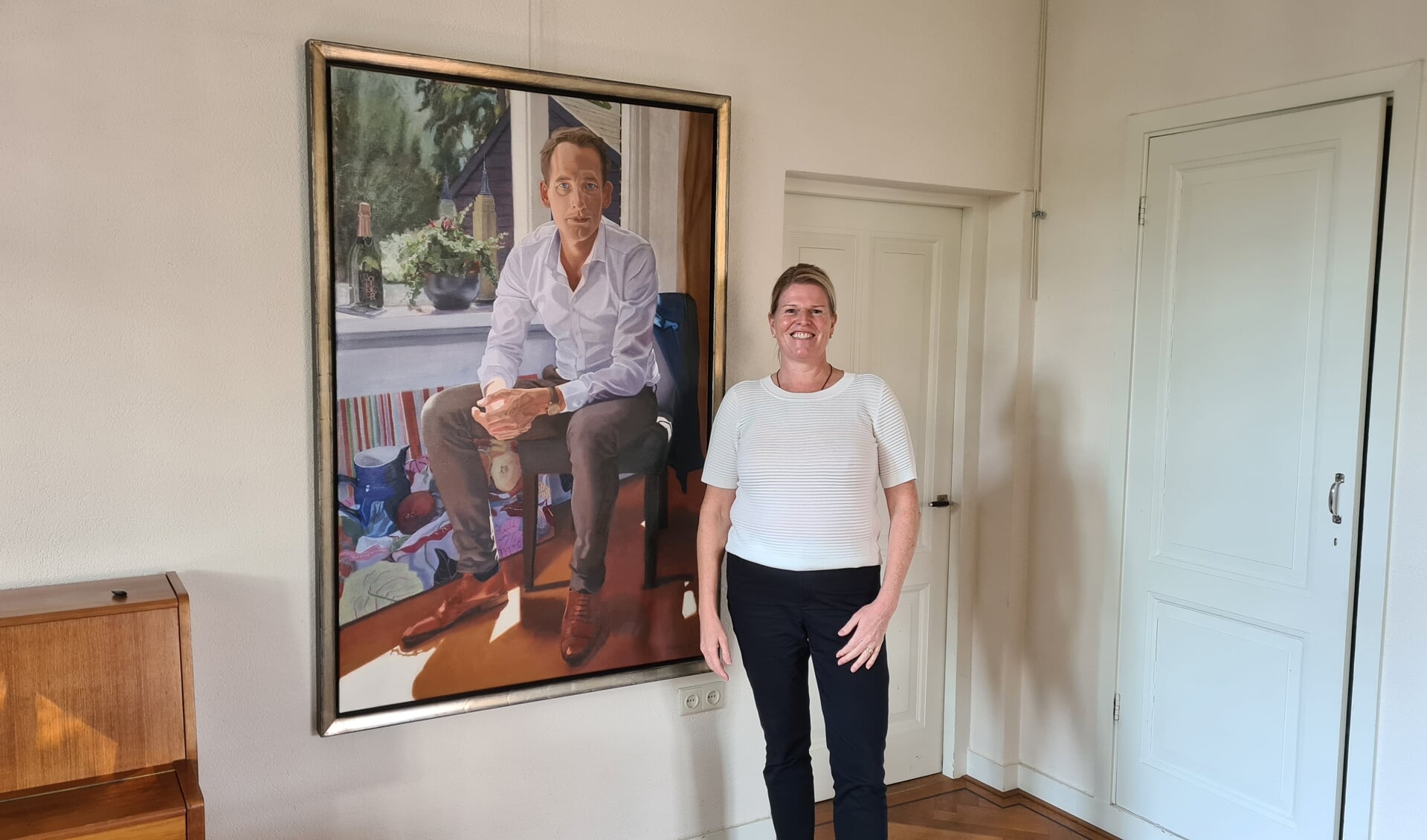 Erika Vermeer naast het portret van haar man. Komend weekend hangt het in Loods 6 in Amsterdam.