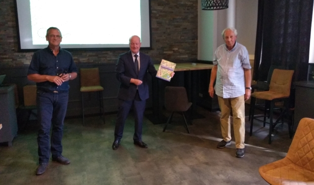 Johan van Impelen (links) en Jan Kleinpenning (rechts) overhandigen het eerste boek aan burgemeester Ruud van Bennekom.