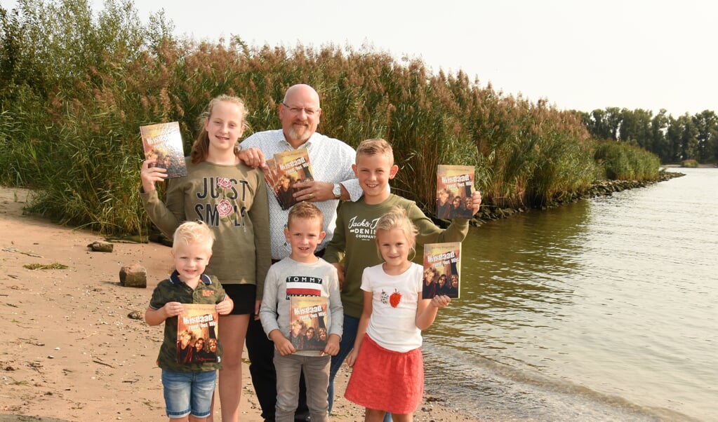 Jan van Wingerden met zijn kleinkinderen, die allemaal het boek vasthouden, bij de Merwede. 